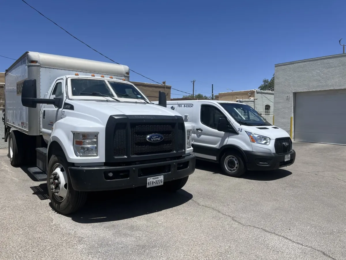 Two white Miracle Delivery armored vehicles parked outside the company's El Paso facility