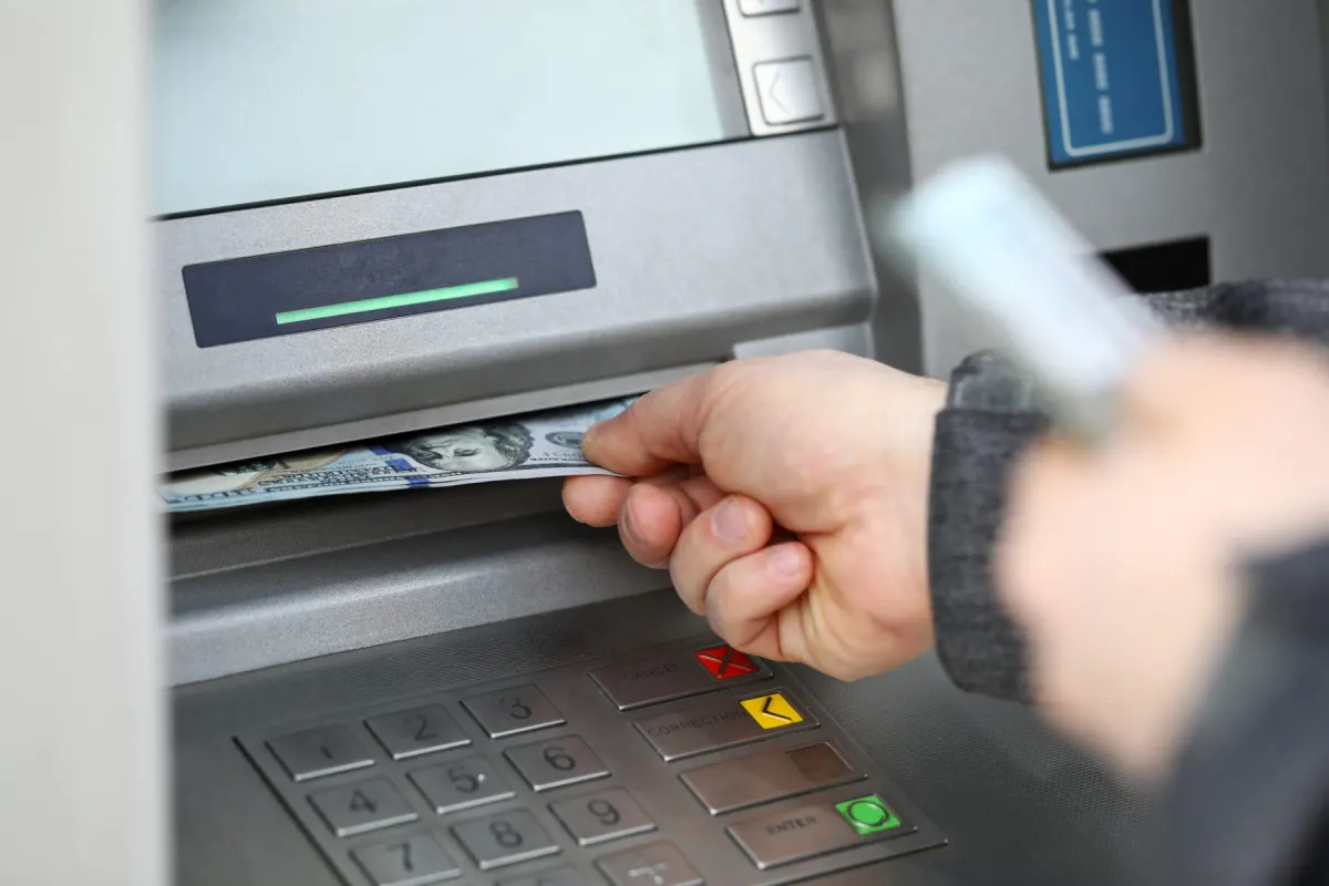 Close-up of a hand collecting cash dispensed from an ATM